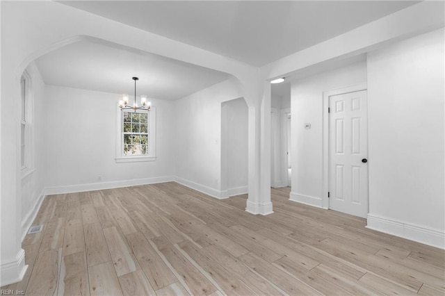 spare room with an inviting chandelier and light wood-type flooring