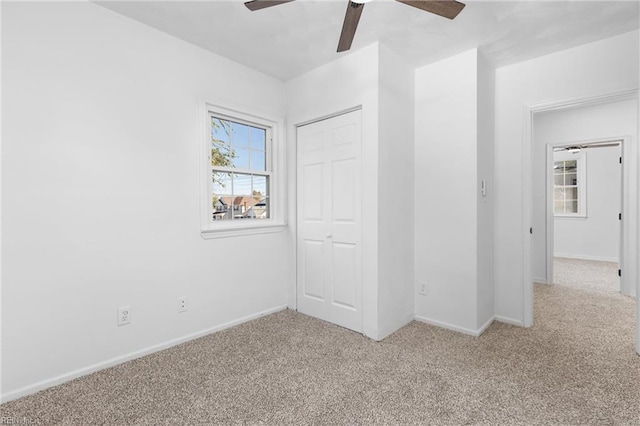 unfurnished bedroom featuring ceiling fan, light colored carpet, and a closet