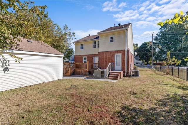 rear view of house with a wooden deck, a yard, and central AC