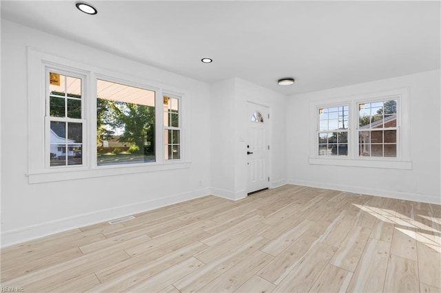 spare room with light wood-type flooring and a healthy amount of sunlight