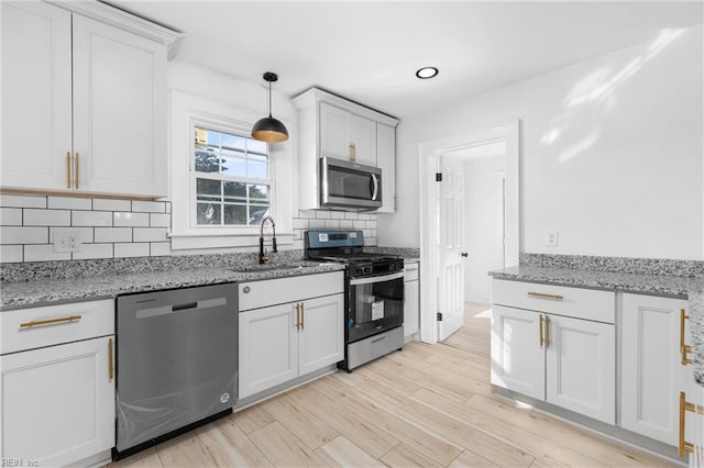 kitchen with appliances with stainless steel finishes, white cabinetry, and tasteful backsplash