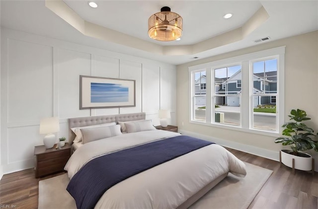 bedroom with dark hardwood / wood-style floors and a raised ceiling