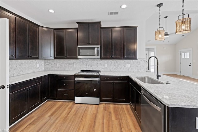 kitchen featuring backsplash, light hardwood / wood-style floors, pendant lighting, sink, and appliances with stainless steel finishes