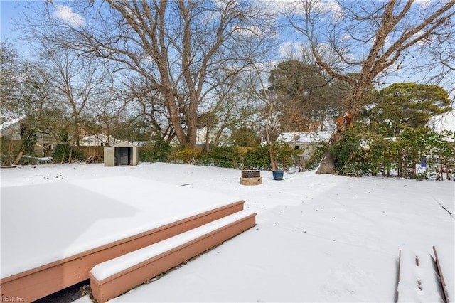 yard layered in snow featuring a storage shed