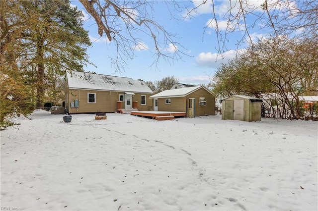 snow covered rear of property with a shed and a deck