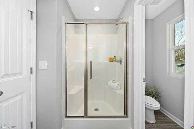 bathroom with hardwood / wood-style flooring, an enclosed shower, and toilet