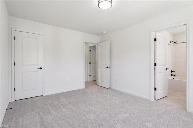 unfurnished bedroom featuring light carpet and connected bathroom