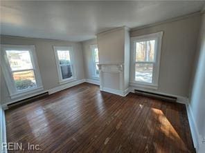 unfurnished living room featuring a baseboard heating unit, dark wood-type flooring, and ornamental molding