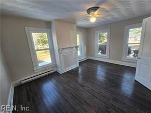 unfurnished living room with a wealth of natural light, a baseboard heating unit, and dark hardwood / wood-style flooring