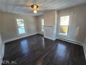 unfurnished living room featuring a baseboard heating unit, ceiling fan, a wealth of natural light, and dark hardwood / wood-style flooring