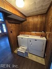 washroom with washing machine and dryer and wooden walls