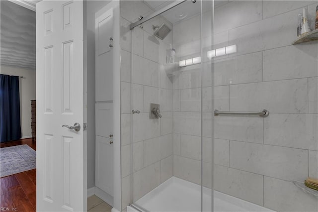 bathroom with a shower with shower door and hardwood / wood-style flooring