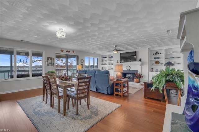 dining space with a textured ceiling, hardwood / wood-style floors, built in features, and a water view