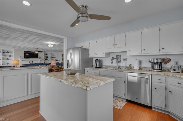 kitchen with white cabinets, light hardwood / wood-style flooring, stainless steel appliances, and a center island