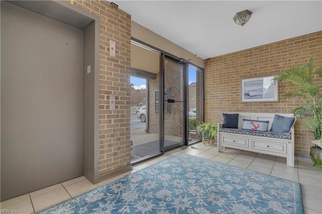 interior space featuring brick wall, light tile patterned floors, and elevator