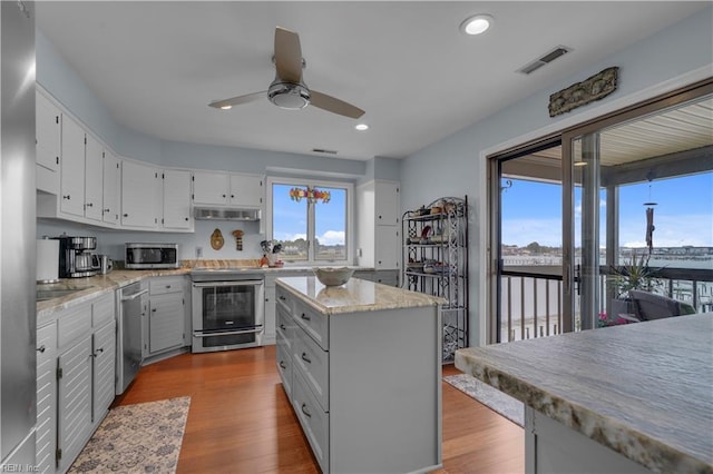 kitchen featuring light hardwood / wood-style floors, white cabinets, appliances with stainless steel finishes, and a center island