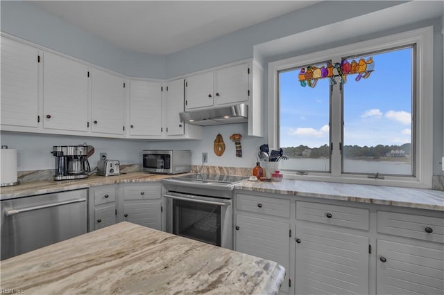 kitchen featuring appliances with stainless steel finishes, light stone counters, and white cabinetry