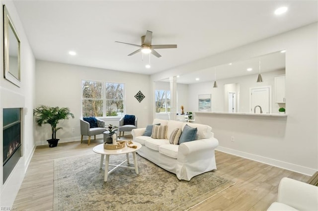 living room featuring light hardwood / wood-style flooring, ceiling fan, and ornate columns