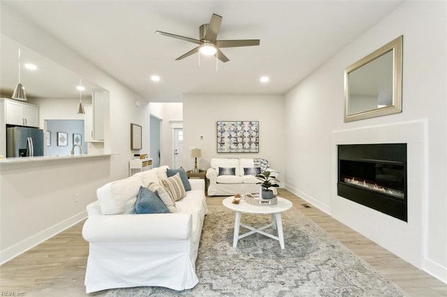 living room with ceiling fan and light hardwood / wood-style floors