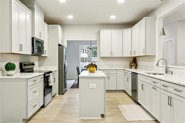 kitchen featuring pendant lighting, sink, white cabinetry, stainless steel appliances, and a center island