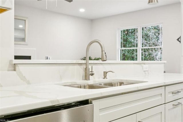 kitchen with dishwasher, light stone countertops, sink, and white cabinets