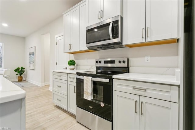 kitchen with white cabinetry, light hardwood / wood-style flooring, light stone countertops, and appliances with stainless steel finishes