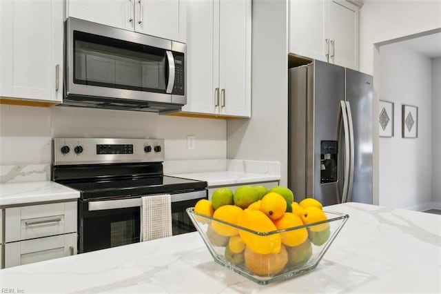 kitchen featuring light stone counters, stainless steel appliances, and white cabinets