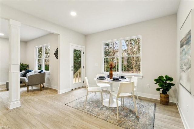 dining room with decorative columns, plenty of natural light, and light hardwood / wood-style flooring