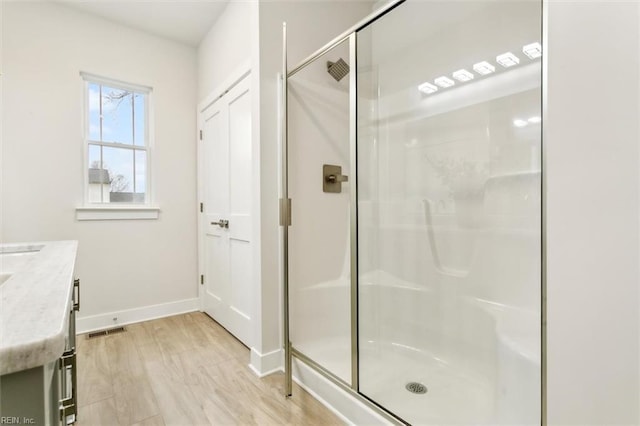 bathroom featuring vanity, hardwood / wood-style flooring, and a shower with door