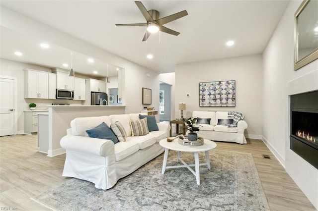 living room featuring light hardwood / wood-style floors and ceiling fan