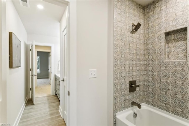 bathroom with tiled shower / bath and hardwood / wood-style floors