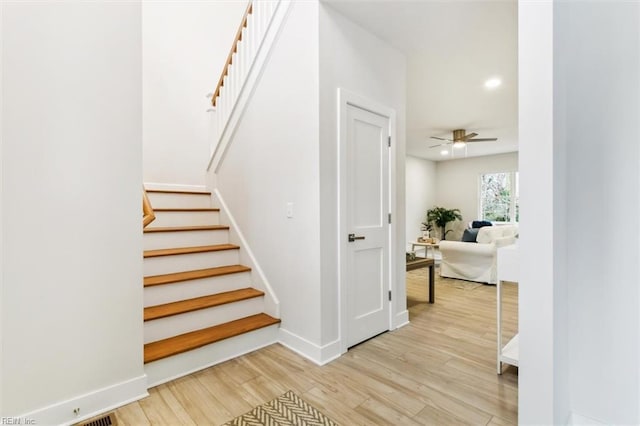 stairway featuring ceiling fan and wood-type flooring