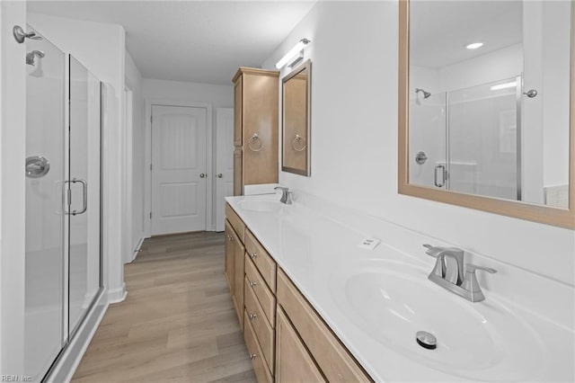 bathroom featuring wood-type flooring, a shower with door, and vanity