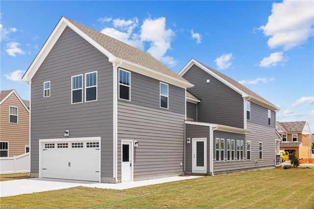 rear view of property with a garage and a lawn