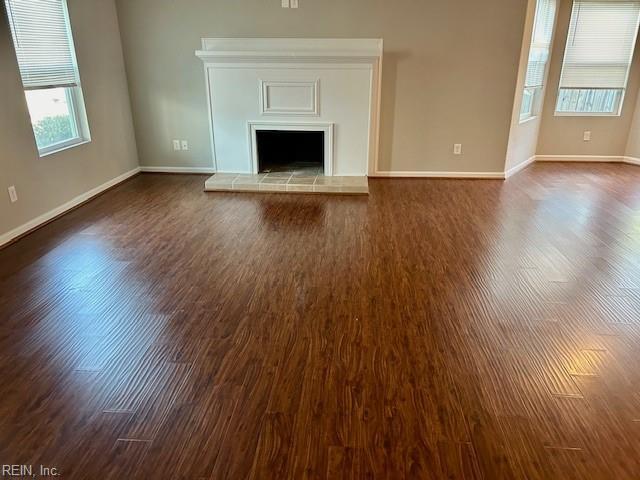 unfurnished living room with dark wood-type flooring and a fireplace