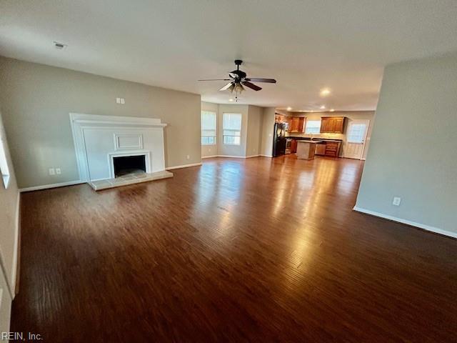 unfurnished living room featuring ceiling fan and dark hardwood / wood-style flooring