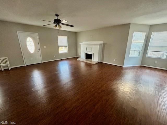 unfurnished living room featuring ceiling fan and dark hardwood / wood-style floors