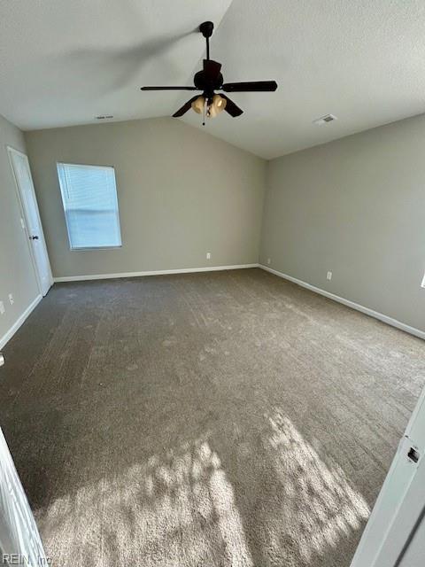 unfurnished room featuring vaulted ceiling, ceiling fan, a textured ceiling, and dark carpet