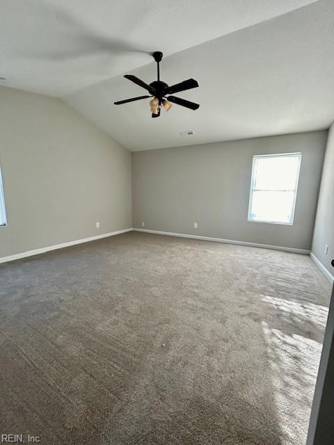 carpeted spare room featuring vaulted ceiling and ceiling fan