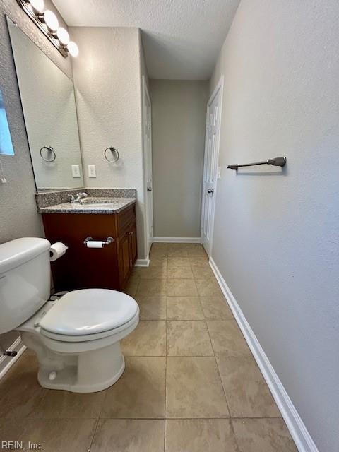 bathroom with toilet, vanity, tile patterned floors, and a textured ceiling