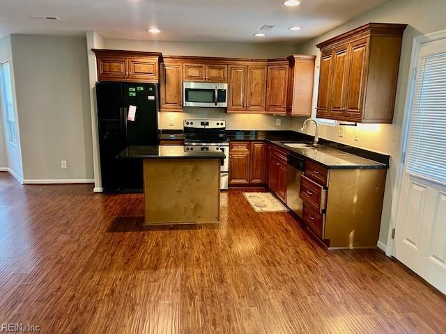 kitchen with dark wood-type flooring, sink, stainless steel appliances, and a center island