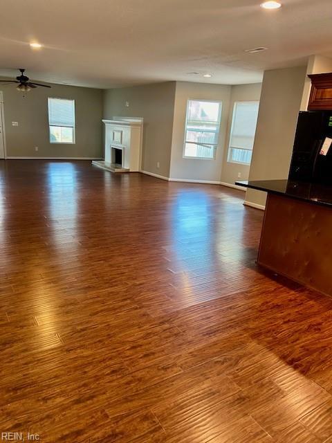 unfurnished living room with ceiling fan, dark hardwood / wood-style floors, and a healthy amount of sunlight