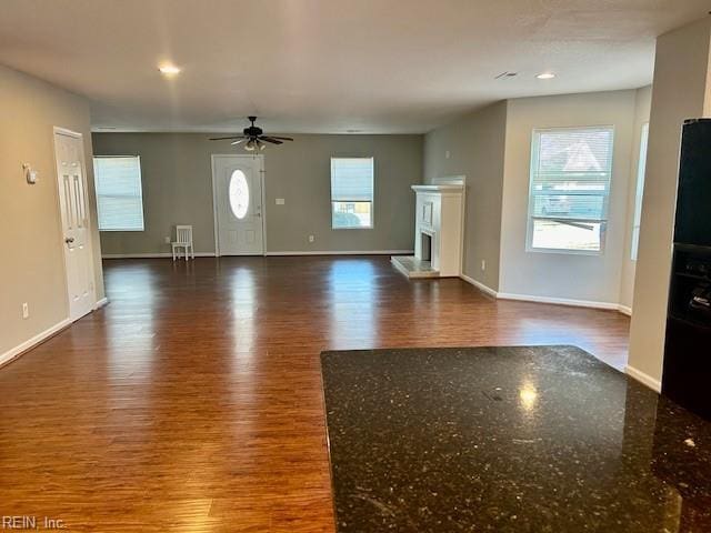 unfurnished living room with dark wood-type flooring and ceiling fan