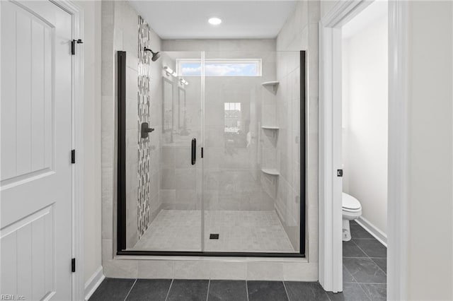 bathroom with tile patterned flooring, toilet, and a shower with shower door