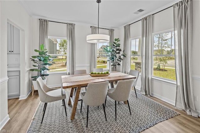 dining space featuring ornamental molding and light hardwood / wood-style floors