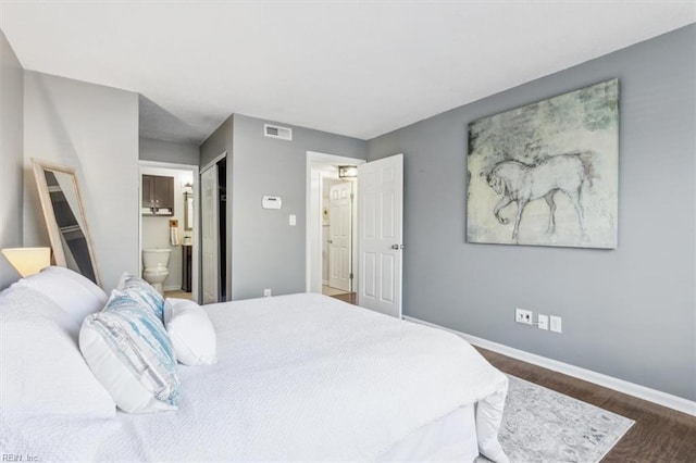 bedroom with dark wood-type flooring and connected bathroom