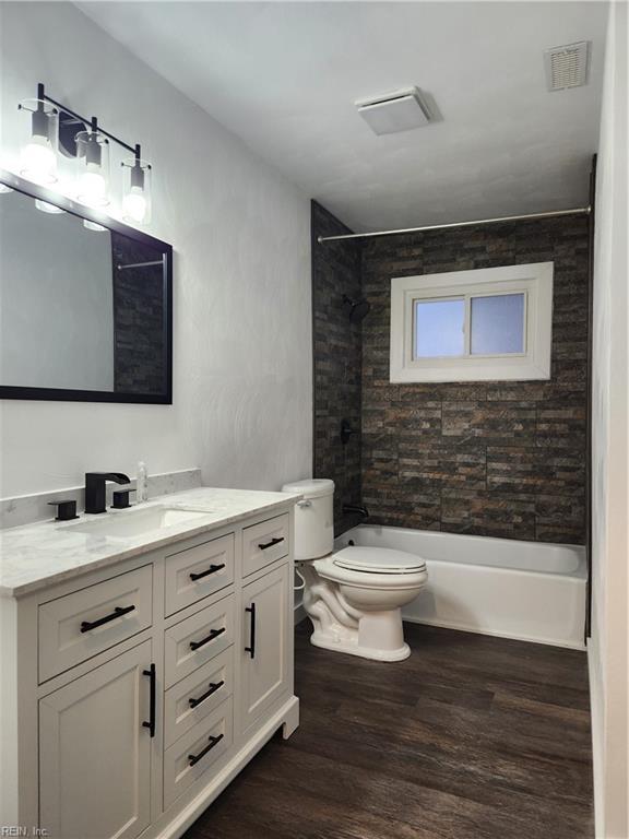 full bathroom featuring tiled shower / bath, wood-type flooring, toilet, and vanity