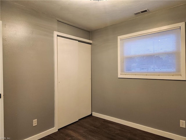 unfurnished bedroom featuring dark wood-type flooring and a closet