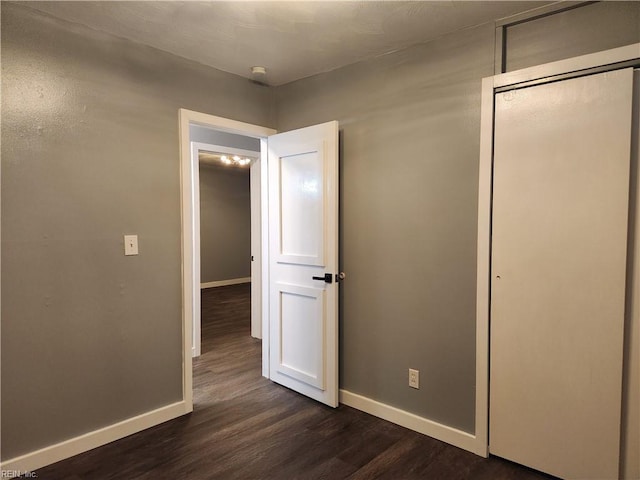 unfurnished bedroom with dark wood-type flooring and a closet