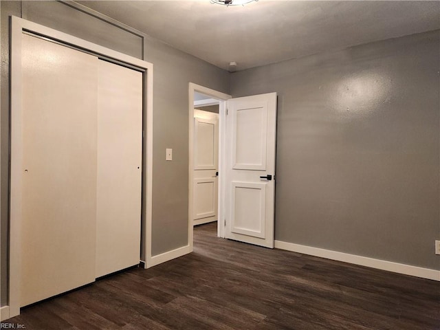 unfurnished bedroom with dark wood-type flooring and a closet